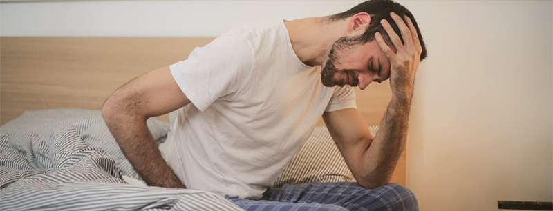 Person sitting on bed expressing pain